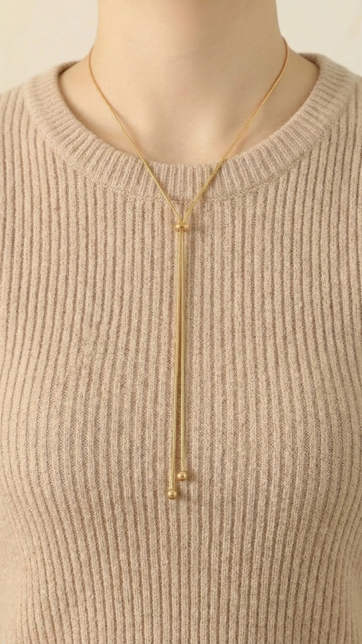 316L Ribbon Snake Necklaceをベージュのリブニットに合わせたAI生成の着用イメージ